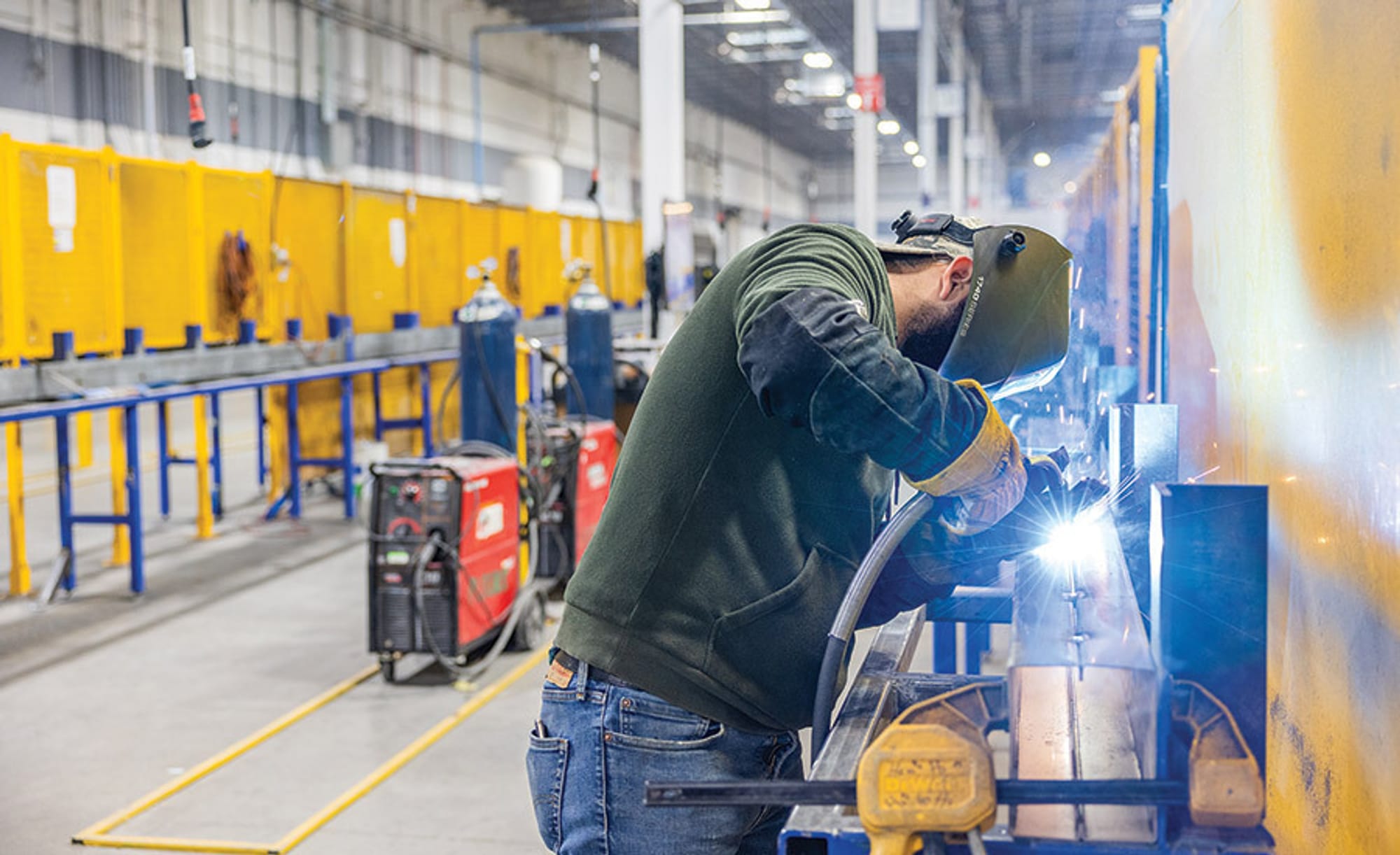 A welder wearing PPE working in a warehouse.
