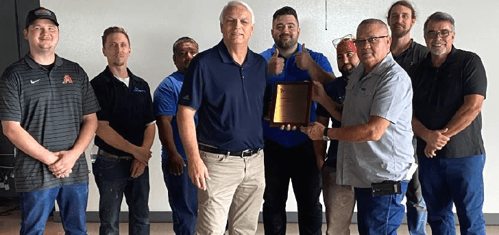 DBC Team posing together with the Liberty Mutual Award plaque