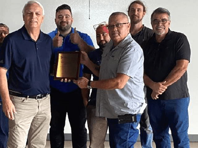 DBC Team posing together with the Liberty Mutual Award plaque