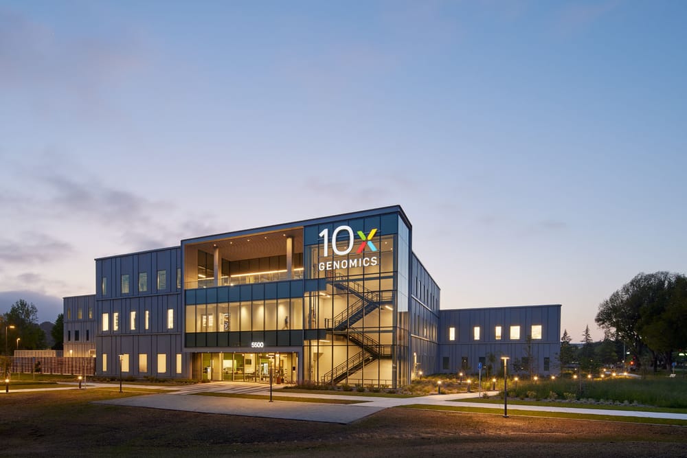 Exterior of biotech facility with lights on during sunset