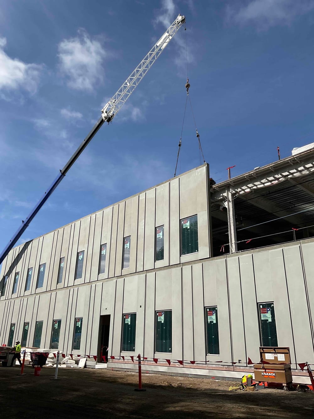 Prefabricated EIFS panel with windows hanging by crane during installation