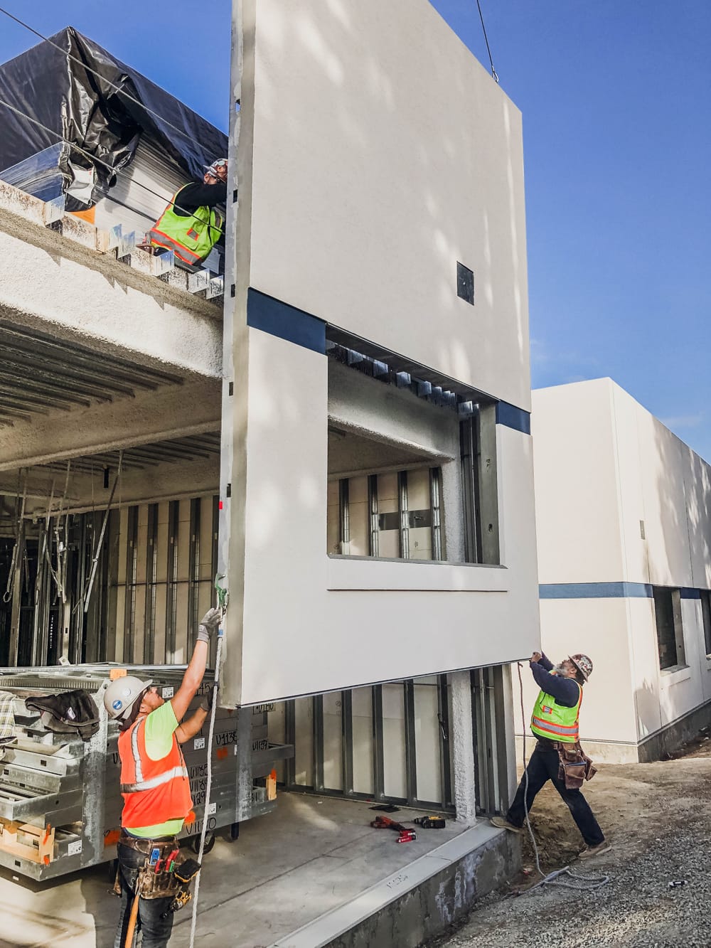 DBC prefabricated panel flying (by crane) into place with three crew members