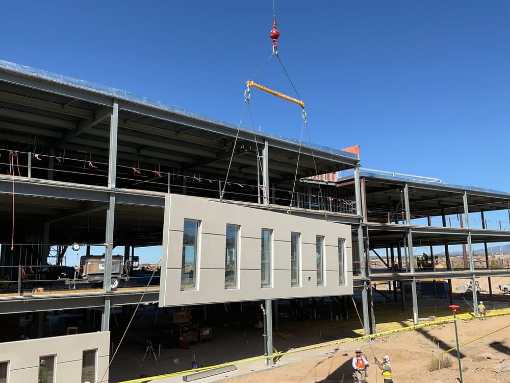 Prefabricated panel with windows hanging by crane during installation