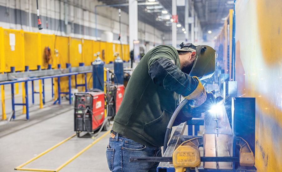 A welder wearing PPE working in a warehouse.