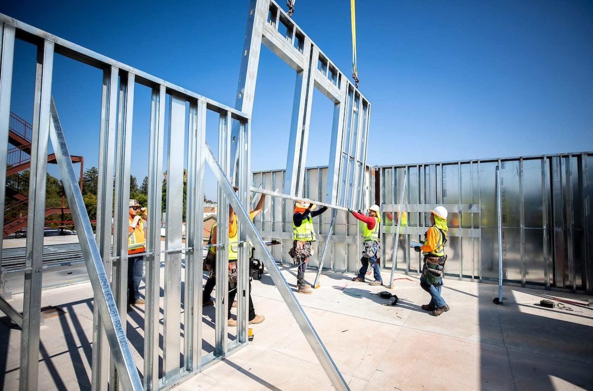 Workers on a job site wearing PPE building with panelized wall systems.