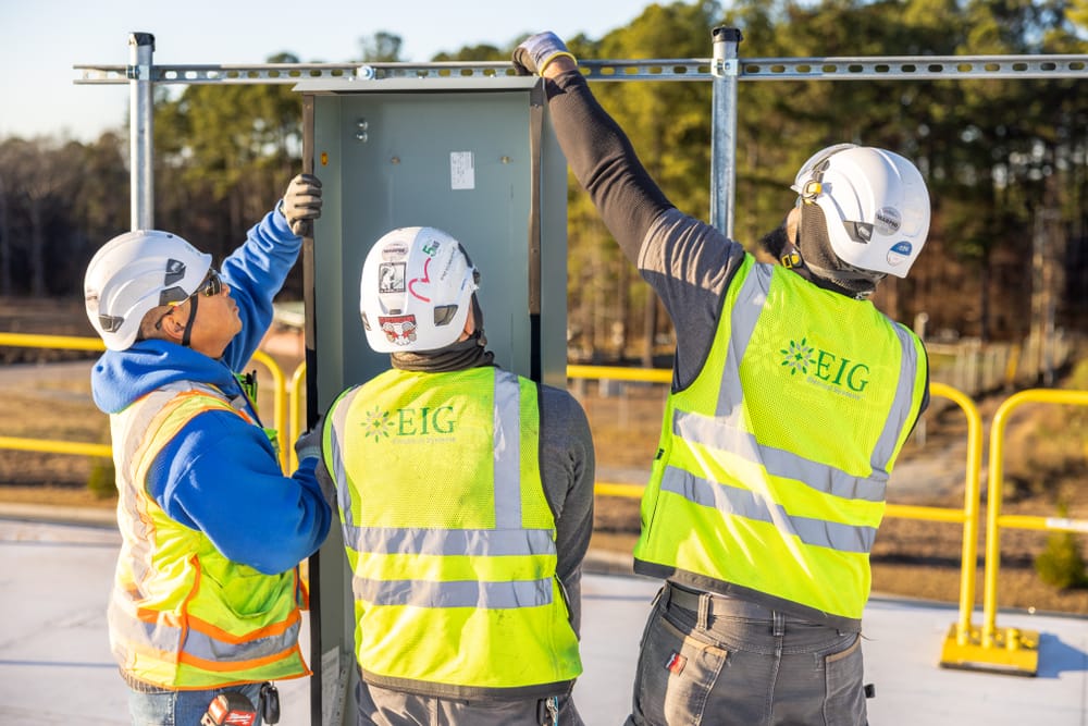 three construction workers installing a solar panel
