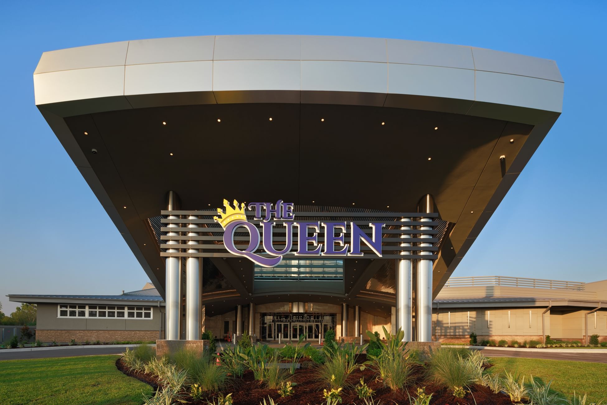 A picture of the front entrance to the hotel,  there is a big purple sign with the name "the Queen" with a yellow crown