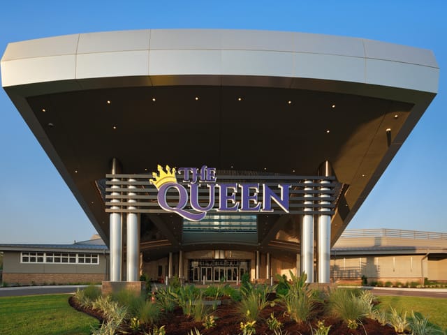 A picture of the front entrance to the hotel,  there is a big purple sign with the name "the Queen" with a yellow crown