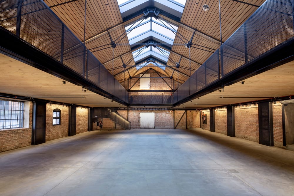 The inside of a two story building with an atrium and a skylight lining the entire roof. The building has exposed brick and steel
