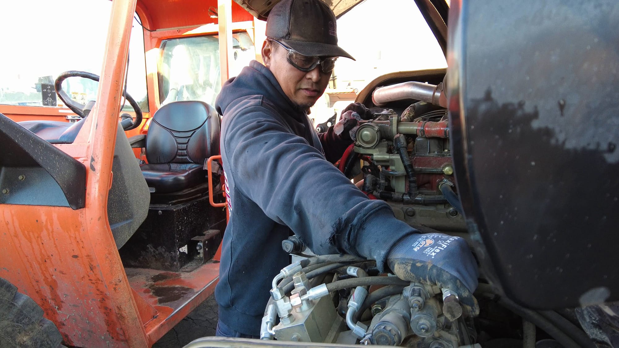 worker reaching into an engine