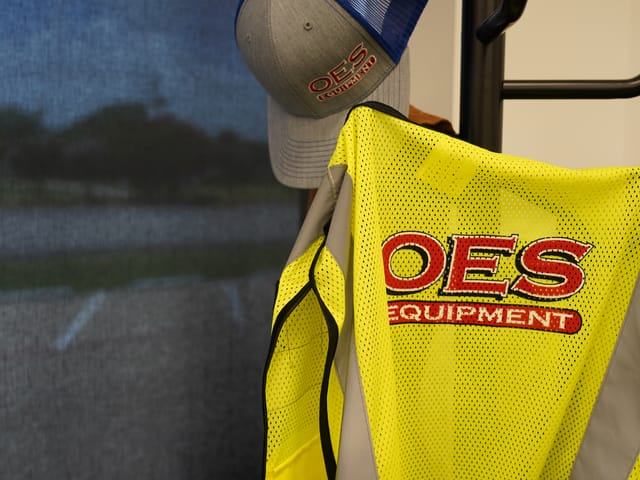 close-up of a yellow safety vest with a red OES logo on the back