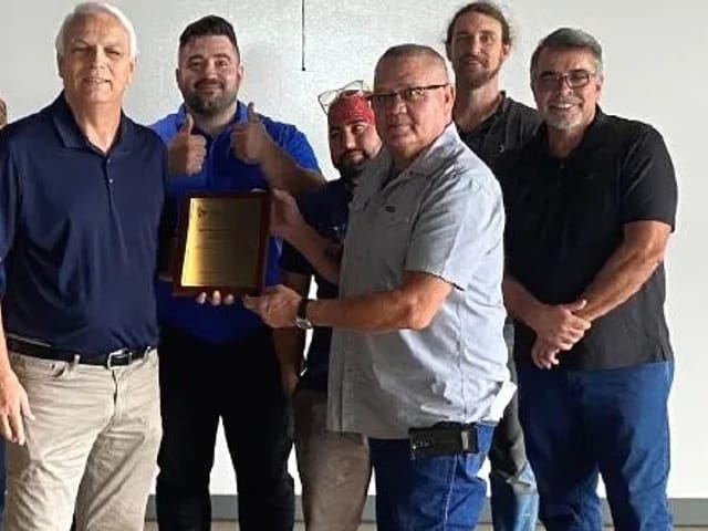 A smiling group pose with an award