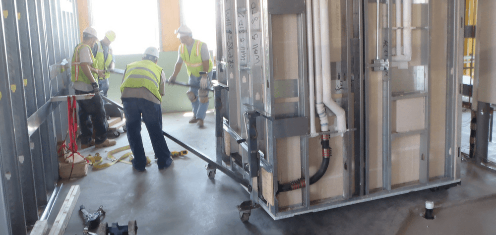 Construction workers installing bathroom pod