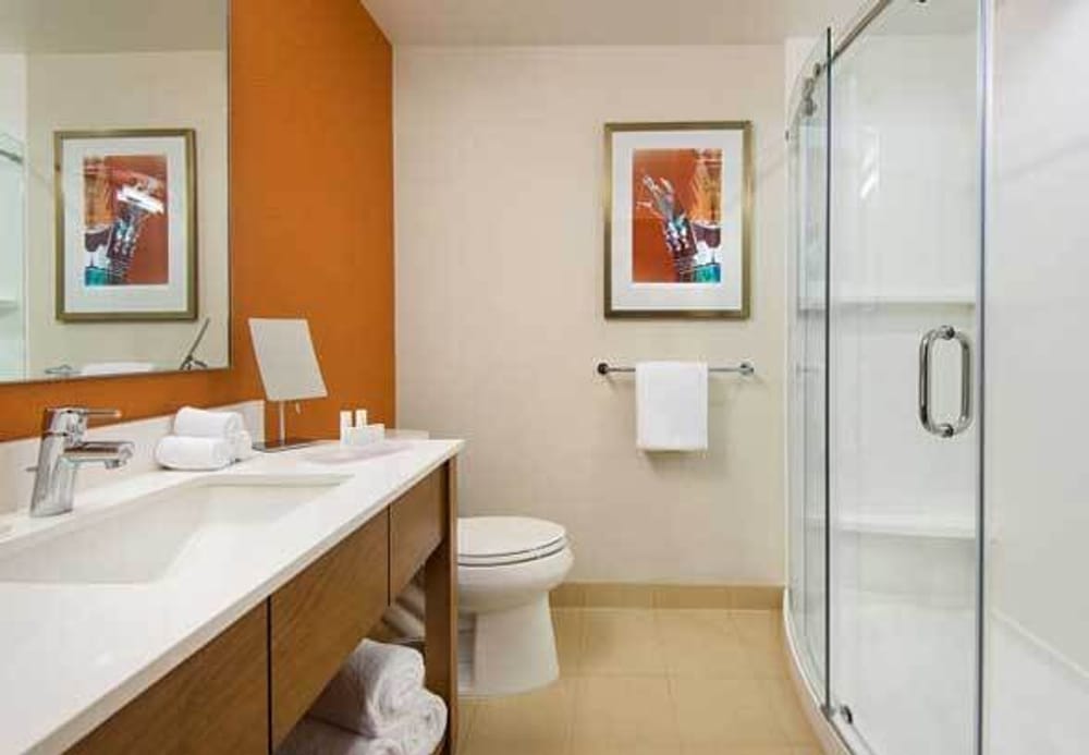 Finished bathroom with orange walls, toilet, shower, and vanity