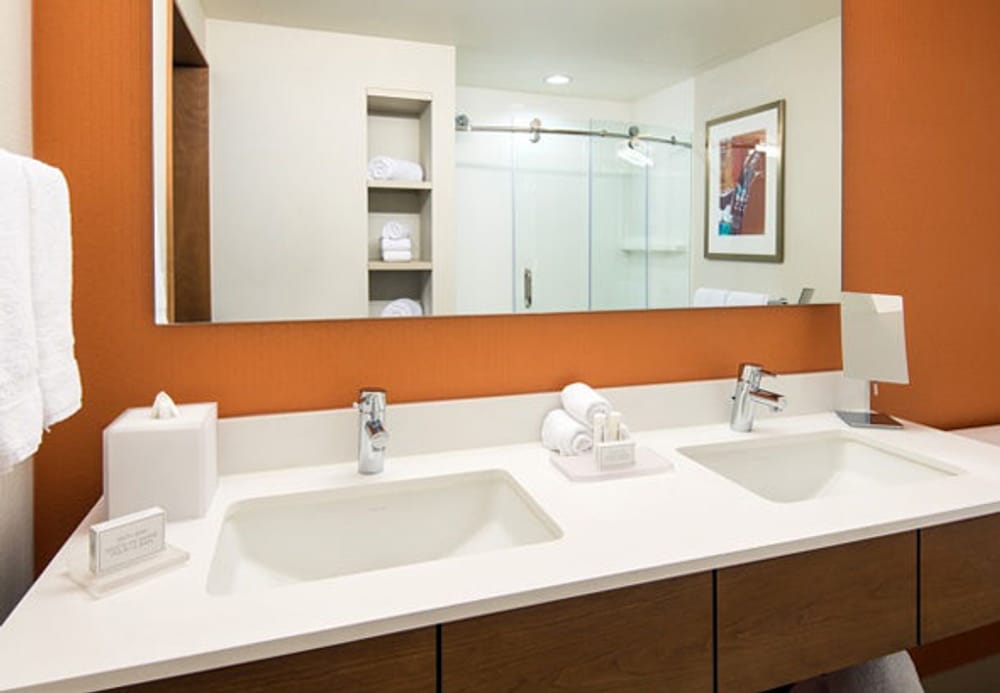 Finished bathroom with orange walls, two sinks and a vanity