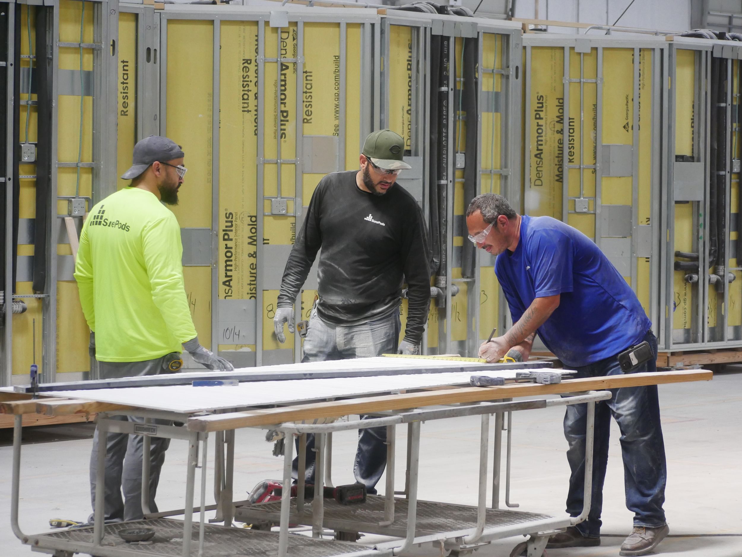 two teammates working on a surepod unit on the facility floor