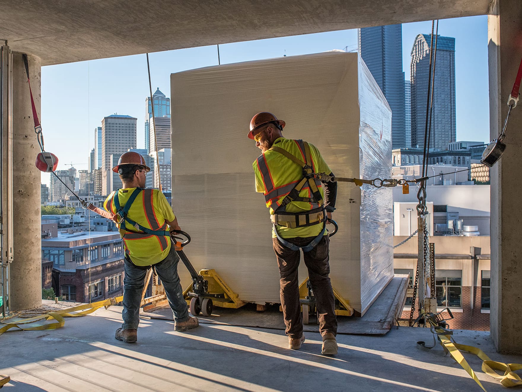 two employees receiving a surepods unit on the side of a building to begin the installation