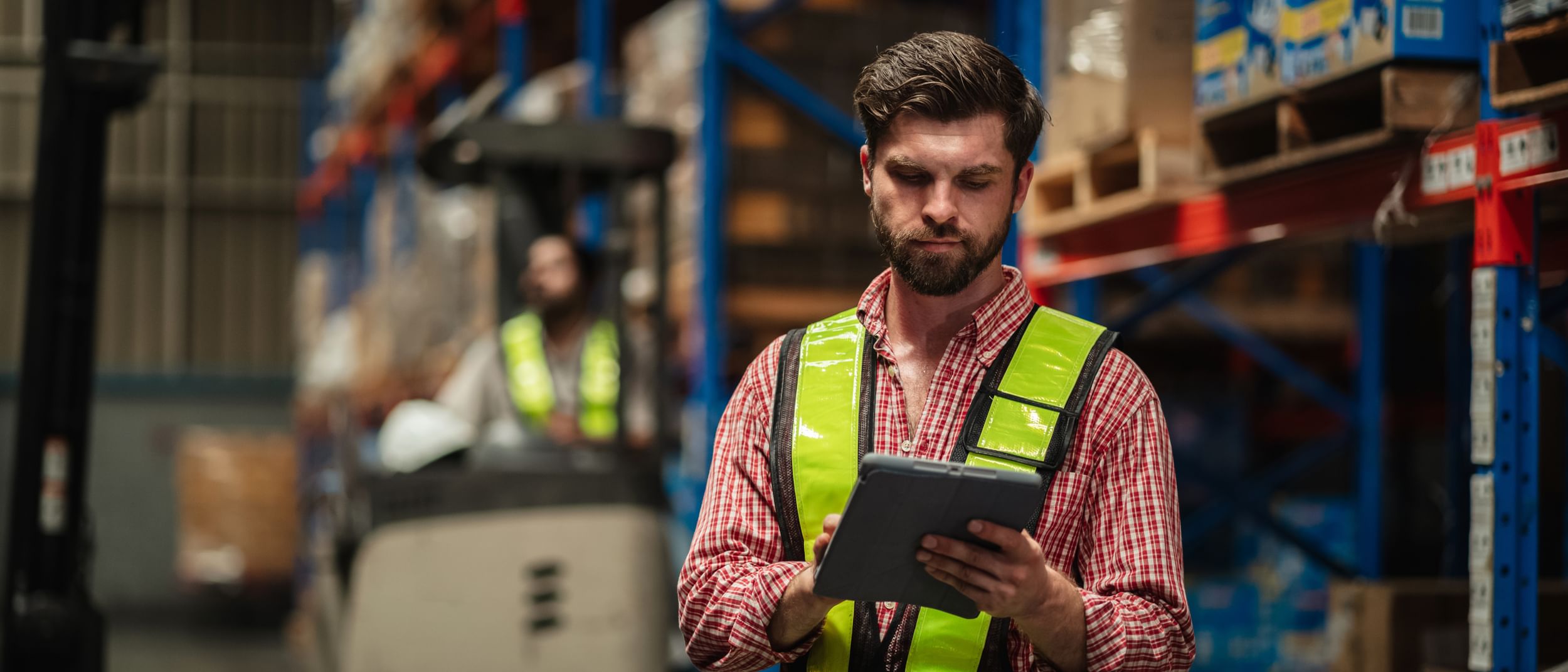 Warehouse technician using tablet to manage inventory and work orders.